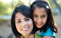 Hispanic mother with daughter on back smiling