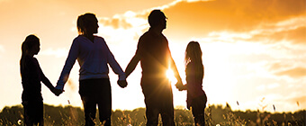 Family in a field holding hands at sunset