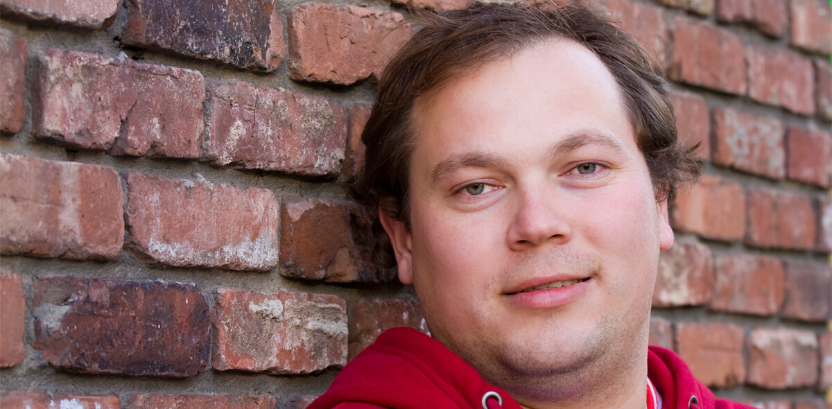 Man in Red Hoodie in front of brick wall