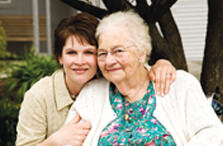 Daughter smiling and hugging elderly mother