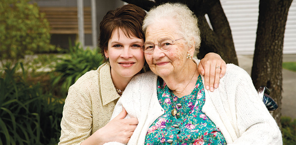 Elderly mother hugged by daughter outdoors