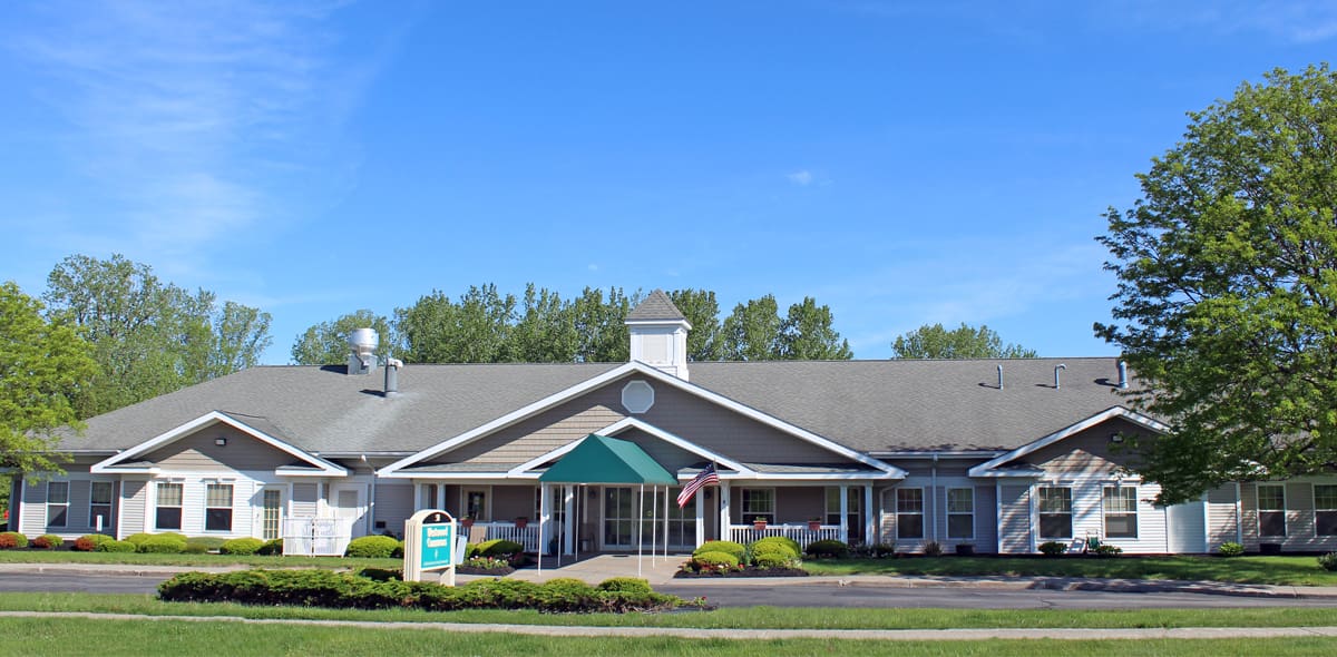 Exterior white building with gray roof with trees and green grass