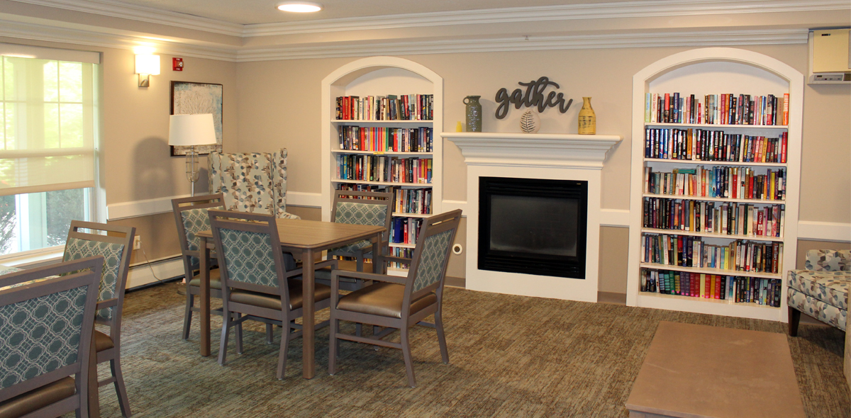 Library with arched bookshelves, white walls and green chairs at dark wood tables