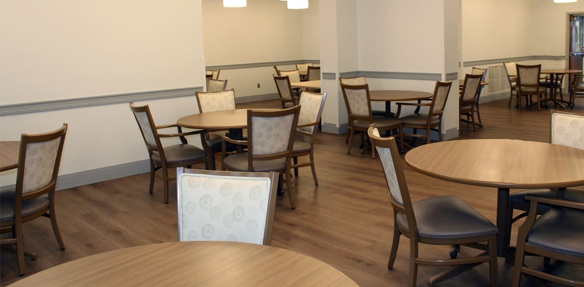 Dining room with brown wooden tables and cream and wooden chairs.