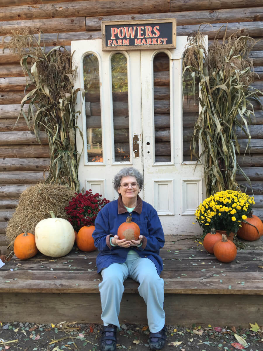 Woodcrest Commons Rosanne Bourne holding a little pumpkin at Powers Farm Market