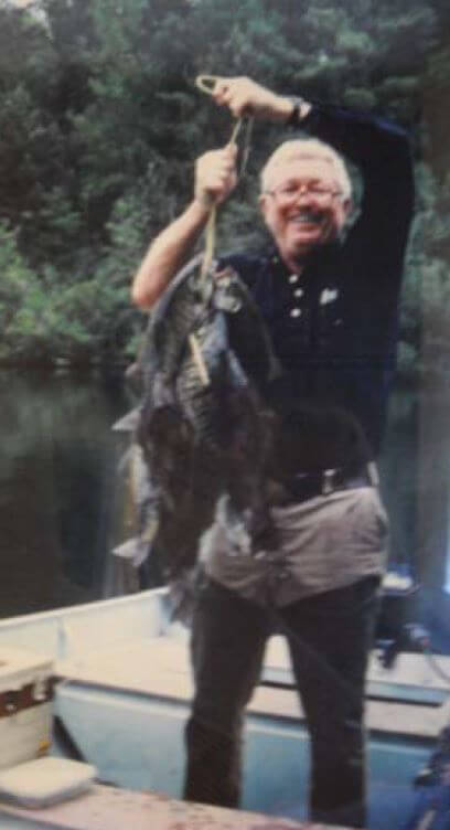 Bob Cox holding a bundle of fish on a boat 