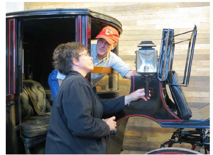 antique carriage collector John Greenall shows Vice President of DePaul Properties, Inc. Gillian Conde some of the intricacies of the Brougham-style Cunningham Carriage