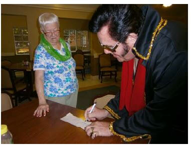 Elvis impersonator Ed Smith writing an autograph for Cambridge House Resident