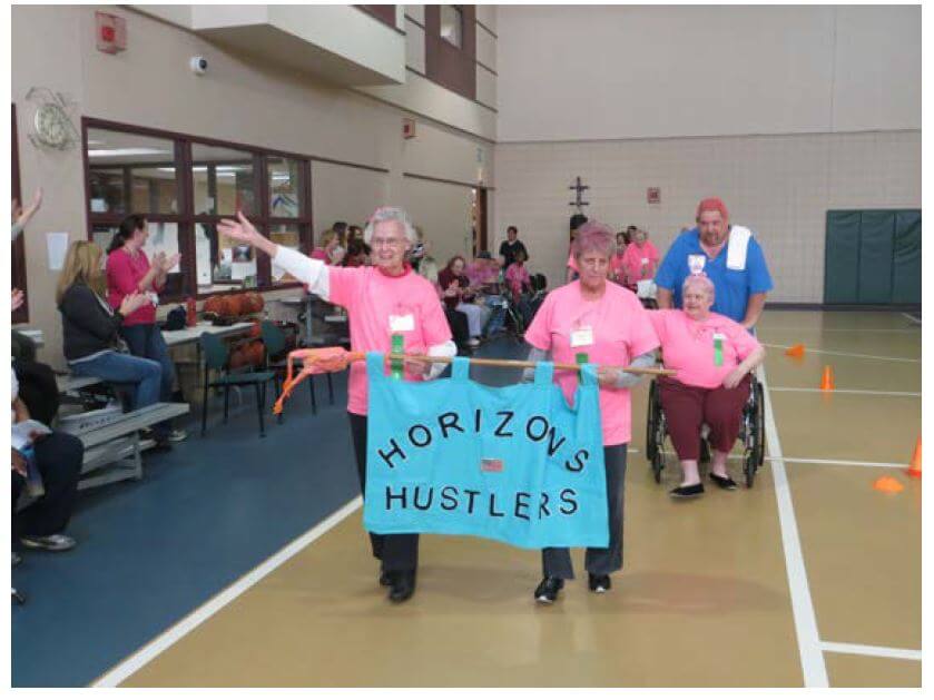 Horizons residents Florine Reddington, Judy Hoffman and Jane MacDonald help kick-off the eighth annual DePaul Senior Olympics with an opening parade holding a sign that says "Horizons Hustlers"