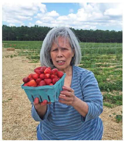 Woodcrest Commons resident Vroria Simpson holding a big container of strawberries