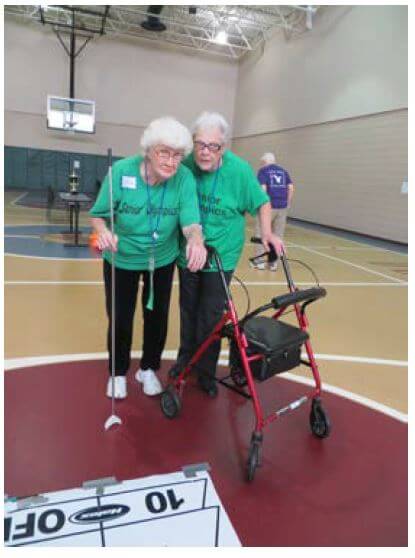 Westwood Commons resident Isabelle Jackson gets some assistance from Receptionist Mary Passarella during a game of shuffle board.