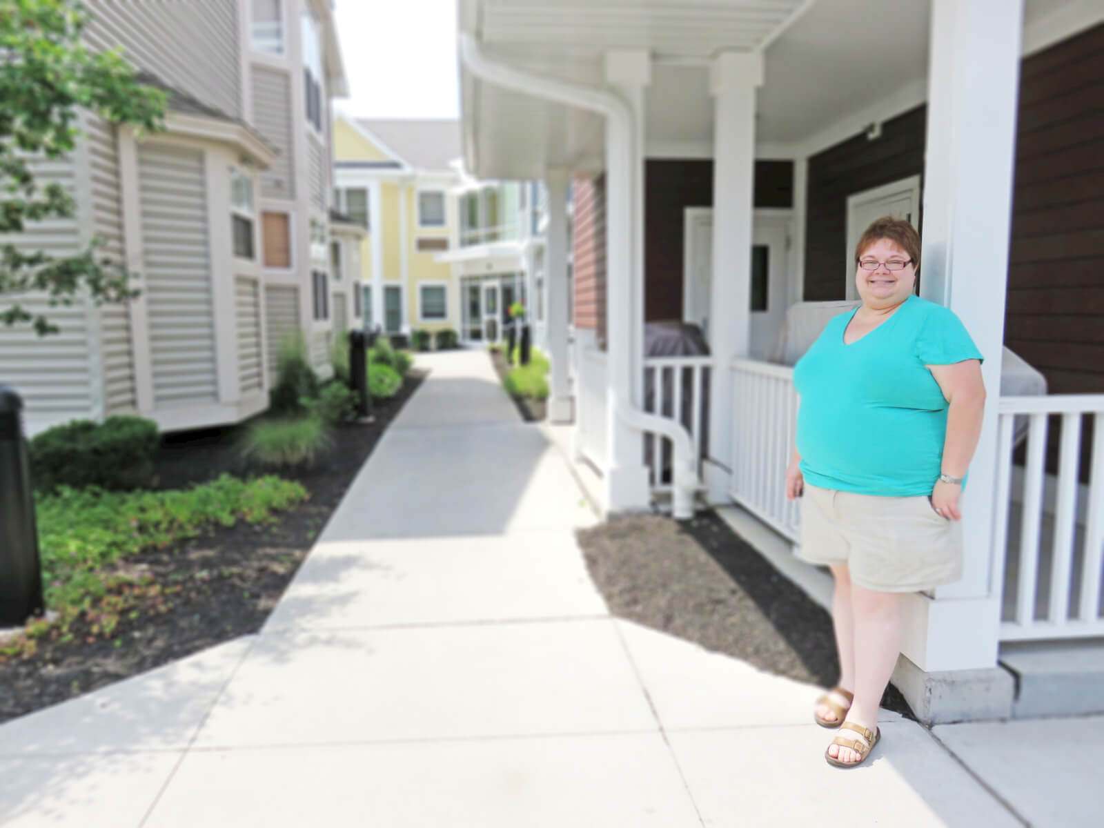 Julia W. posing for a photo next to the Neighborhood of the Arts Apartments 