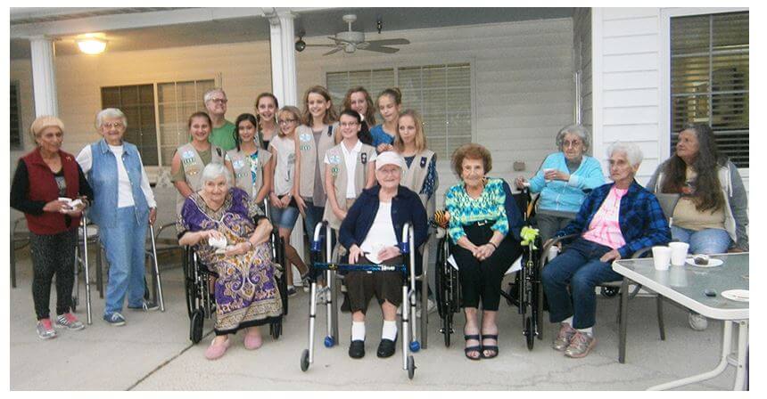 group photo of Girl Scouts and residents celebrating the culmination of the garden project with a pinning ceremony.