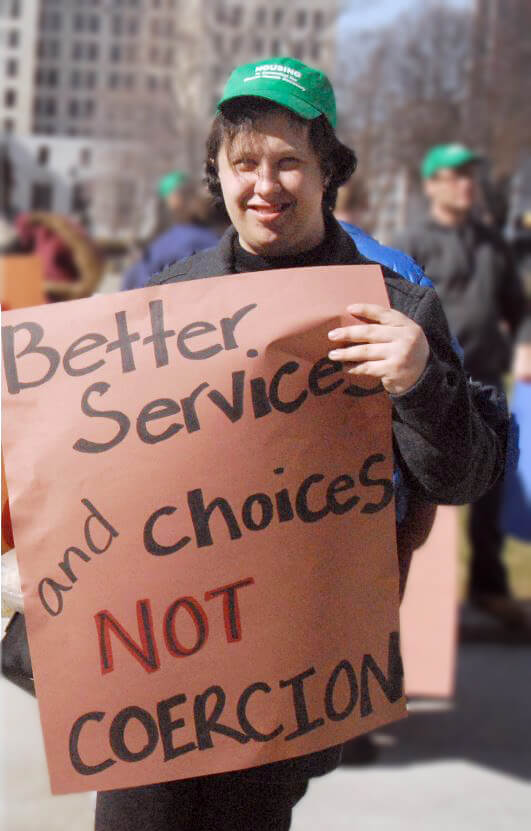 Photo of DePaul client marching in Albany holding a sign saying "Better services and choices, not coercion"