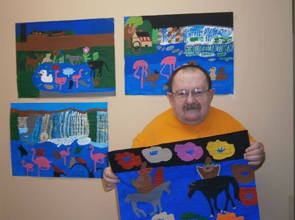 Heath House resident Roger Green showing off his paintings
