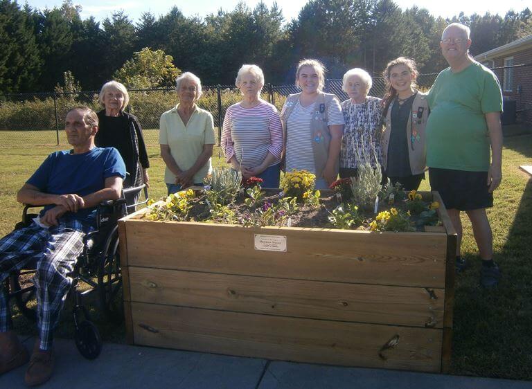 Journey and Madison are pictured with Wexford House residents behind the flower bed they built