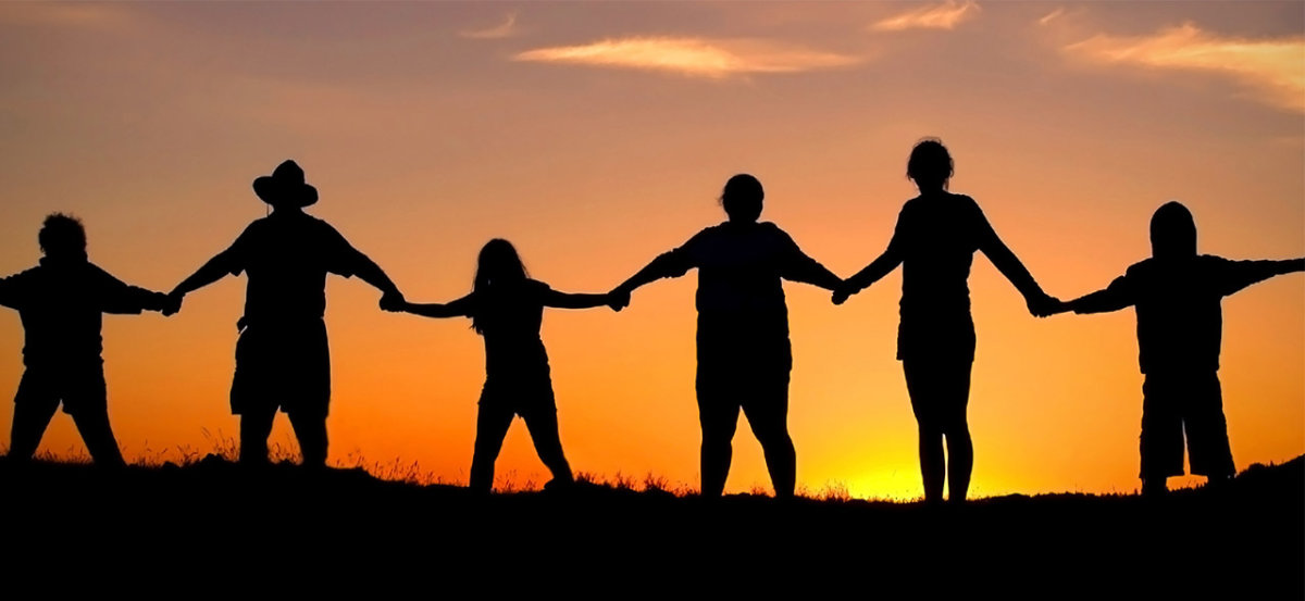 People holding hands in a line during a sunset