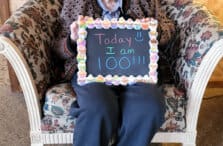 An old woman holding a sign.