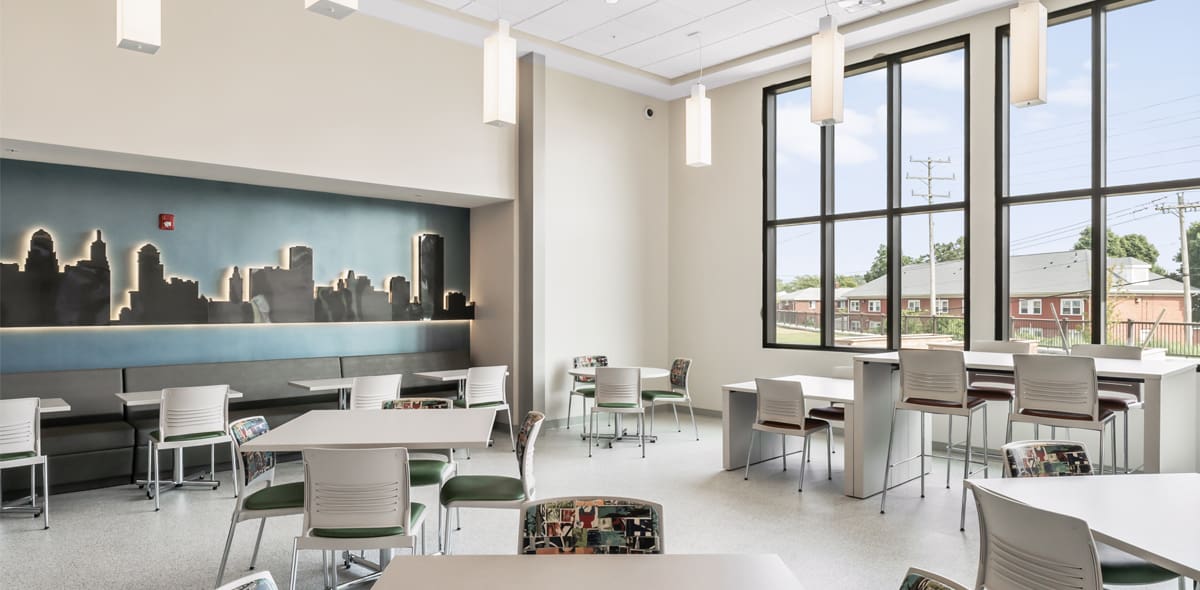 Room with blue and black skyline mural, large windows and chairs with tables