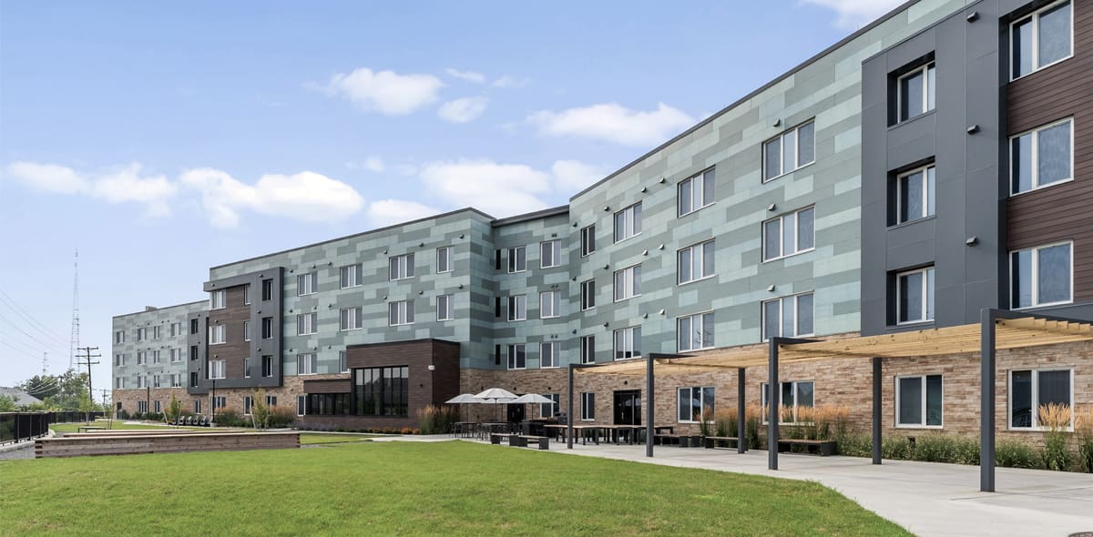 Green building exterior with green grass and blue cloudy sky