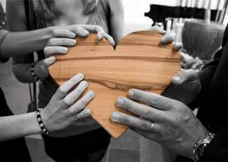 Black and White Hands Holding Color Wooden Heart