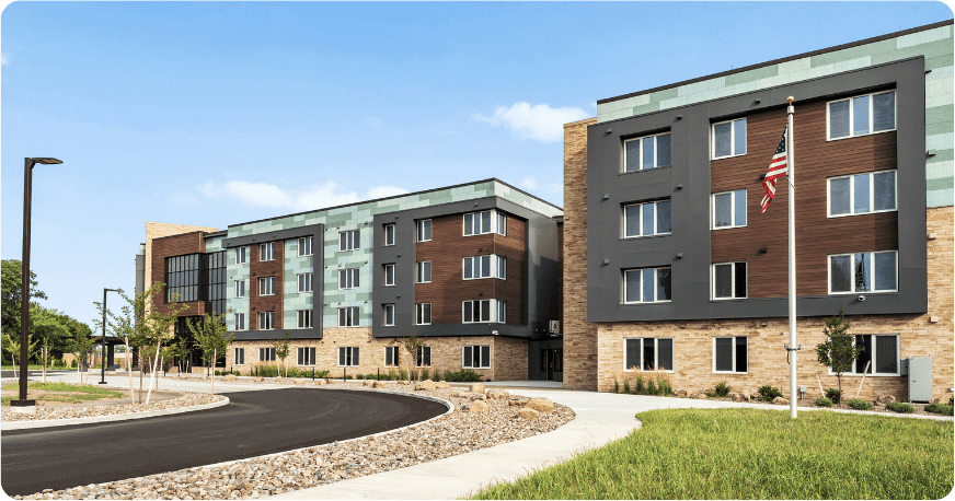 Green and gray building with blue sky.