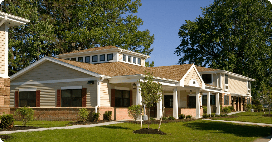 Tan and yellow building with blue sky and trees in background.